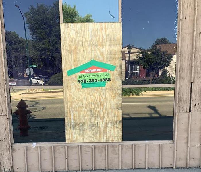Local business with a window boarded up due to vandalism